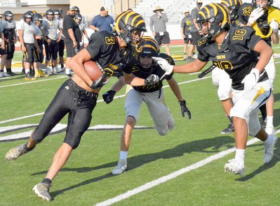 Snyder junior Jaden Hernandez (left) prepared to evade the tackles of junior Hunter Stewart (center) and Isael Rios during practice at Tiger Stadium Monday. The Tigers will host Slaton at 7:30 p.m. Friday for the season opener.