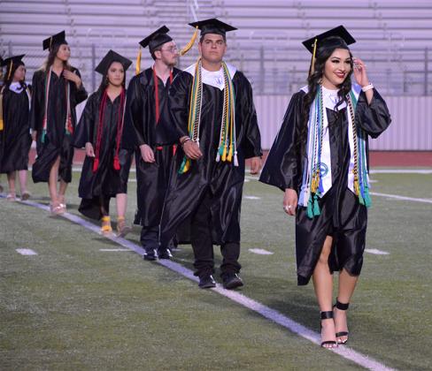 Class of 2021 graduates including Kimberly Cortes (right), Jaxson Collier (second from right) and others made their way onto the foorball field for their graduation ceremony.