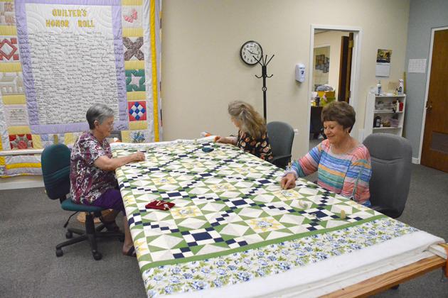 Anna Poe, Ruth Morrells and Carolyn Martin (l-r) worked on a quilt at the senior center for its upcoming May Day fundraiser.