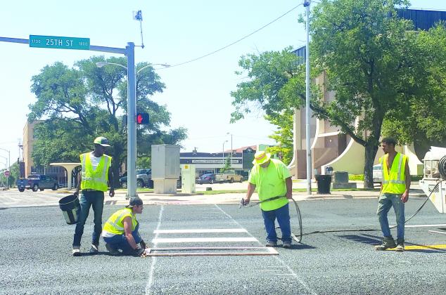 Workers use stencils to paint a crosswalk on 25th Street at the intersection with Ave. R Thursday afternoon. The workers, employees of Flat Line Inc. of Tye, include (l-r) Xavier McCarthy, Anthony Neely, David Blanco and Trey Poteet.