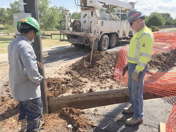 Primary Utility Services employees Andy Rivera (left) and Jimmy Ashley set a utility pole on Friday in the 2900 block of College Ave.