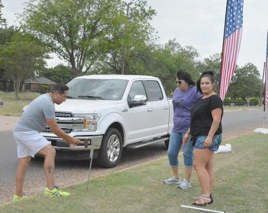 Chamber of Commerce employees (from left) Josh Ortegon, Sandra Salinas and Summer Grimmett set up flags along the entrance to Towle Park in preparation for the Fourth of July.