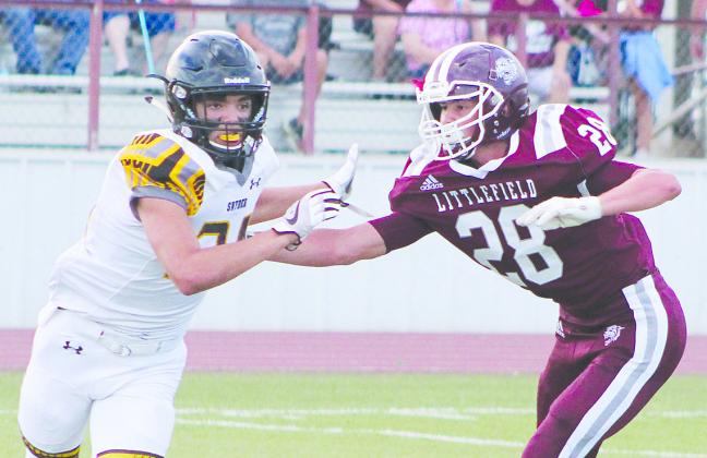 Snyder’s Jayden Samaniego (34) attempts to get away from Littlefield’s Chris Brown during Friday’s game.
