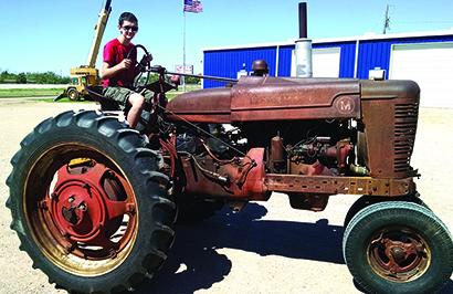 Austin Reynolds with the tractor in August, before he began the restoration project.