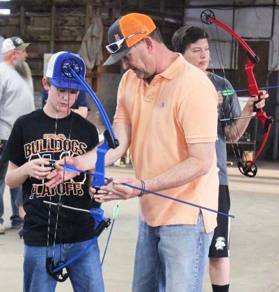 Dylan Billingsley received instructions on how to place an arrow into a bow from 4-H archery coach Mike Hale.