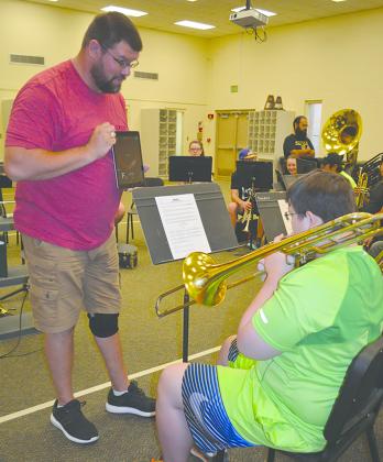 Snyder High School band director Jeremiah McCurdy (left) helped trombonist Travis Thompson with tuning during rehearsals for new band members today.