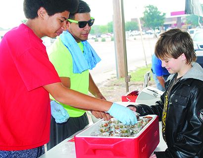 From left, James Roden, Avian Gutierrez and Robert Turner sort barbecue sauces at last week’s barbecue and bake sale.