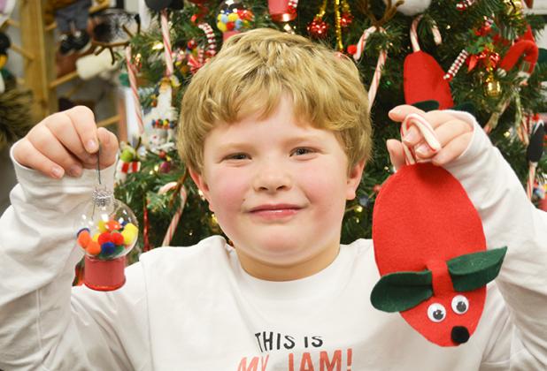 Rylan Martin holds a gumball machine ornament and a mouse candy cane ornament he helped make in Sandy Holmes kindergarten classroom at Ira ISD. 