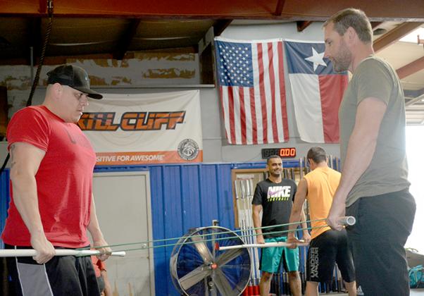 Chris Hernandez (left) and Jason Grizzle work on a resistance exercise to prepare for Saturday’s Power Hour competition at CrossFit Snyder. 