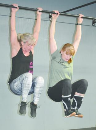 Tanya Lytle (left) and Tammy Tyrrell lifted their legs during a team workout.