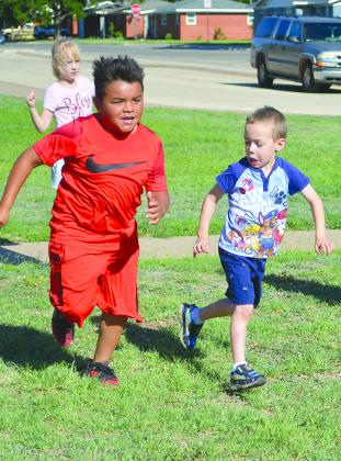 Ethan Garza (left) and Noah Whitacre raced for third base while playing kickball during a CrossFit Kids class this morning.