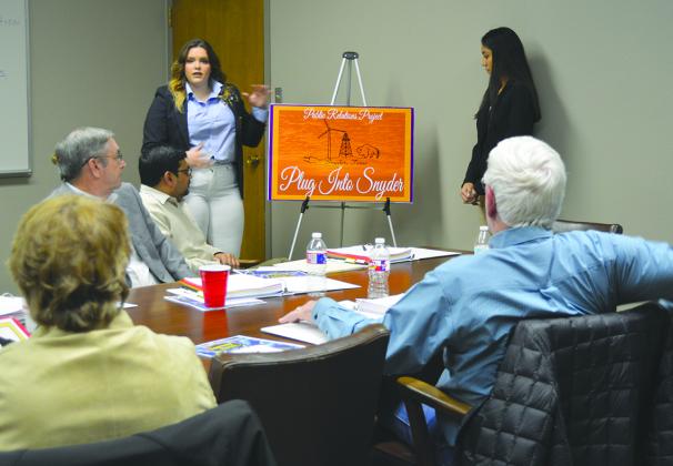Snyder High School DECA students Sara McClain (left) and Lucero Rodriguez presented their Plug Into Snyder campaign to the Snyder Chamber of Commerce board of directors Monday night. The campaign includes brochures, information packets and social media pages to inform visitors and new residents about what Snyder has to offer.
