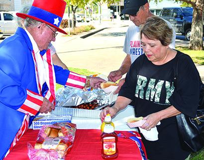 C.D. Gray (left), dressed as Uncle Sam, served hot dogs to Nancy Candanoza and Andy Candanoza on the Scurry County Courthouse lawn as part of the Your Vote Counts campaign today. Hot dogs were free for anyone who voted today, the first day of early voting.