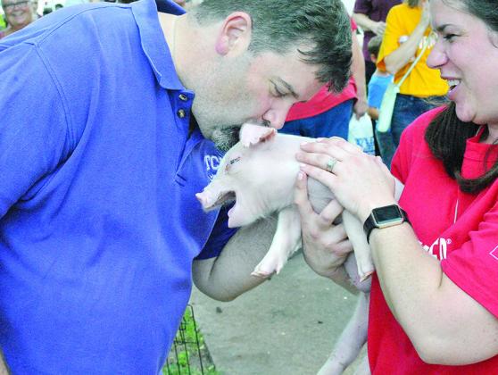 Snyder Daily News Publisher Bill Crist (left) kissed a pig held by Scurry County United Way Executive Secretary Sheila Hale.