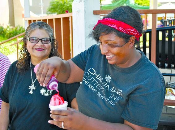 Esmeralda Maldonado (left) watched as Georgette McGinty filled a snow cone order during the Scurry County United Way’s County Fair on the Square Saturday afternoon.