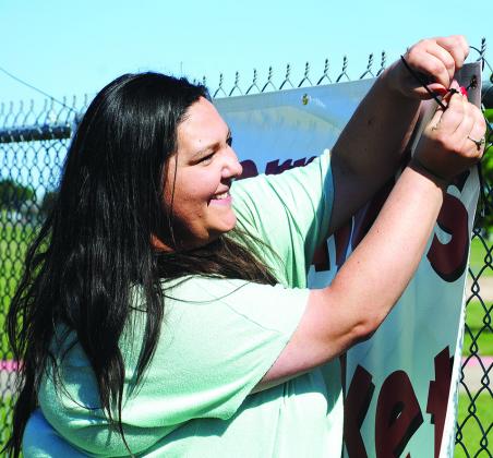 The Coliseum Event Coordinator Kiera Harris hangs a banner for the Snyder Farmers Market on the fence along The Coliseum grounds. The first farmers market of the year will begin at 8 a.m. Saturday. 