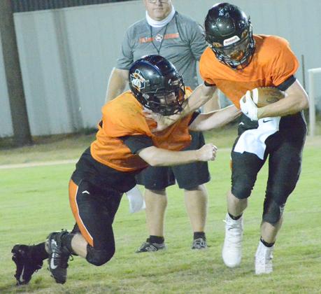 Ira junior Gage Peterson (right) used a stiff arm to escape the tackle of junior Luke Grant during Midnight Madness at Bulldog Stadium Friday.