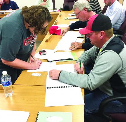 Hermleigh ISD Business Manager Marci Beard (left) looked over paperwork after David Digby and Joe Taylor were sworn in as the newest member of the Hermleigh ISD board of trustees Thursday night.