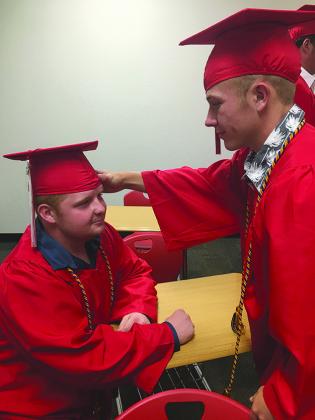 Hermleigh High School senior Colton Messick (left) helped adjust Tracker Dugan’s cap prior to graduation Friday night.