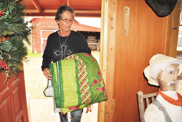 Scurry County Federal Credit Union employee Bonnie Stokes carried a quilt into the bunkhouse at Heritage Village Monday to use during the Christmas decoration fundraiser on Dec. 1 during the Heritage Village Christmas. Four financial institution will each decorate a building and the community will vote for the best decoraitons through donations. A team from Prosperity Bank will decorate the Redwood Chapel, West Texas State Bank will decorate the Cornelius Dodson House living room and AimBank will decorate t
