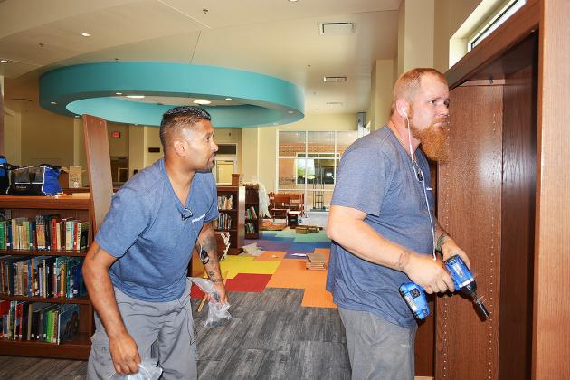 Gabriel Singh (left) and Rodney Baughan, with Indeco Sales, installed shelves in the new Snyder Junior High School library on Wednesday.