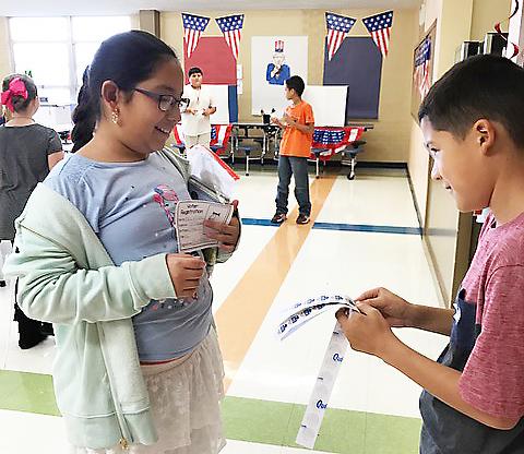 Snyder Intermediate School fourth grade student Jonathan Carillo (right) gave Alyssa Olivarez an “I Voted” sticker during the school’s mock presidential election Monday. Students learned all aspects of the voting process, from registering to vote to voting at the polls.  Donald Trump received the most votes.