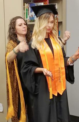Keva Fowlkes (left) helped Ira High School senior Alyssa Cowen with her cap and gown prior to the start of graduation ceremonies Friday.