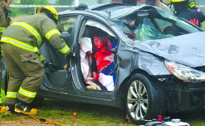 Snyder Fire Department Firefighter Andres Medina (left) began to extract the “deceased victim,” Alyssa Cowan, from the vehicle during the Shattered Dreams presentation at Ira Thursday.