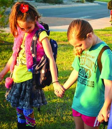 Ira third grade students Mia Schultz (left) and Landry Cumbie pray before school during Wednesday’s See You at the Pole.