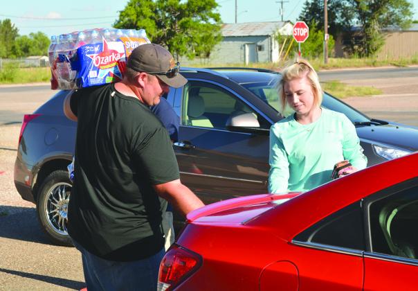 Brad Bawcum (left) helps Jordan Mathis load bottled water into her car at the Ira First Church of God Tuesday evening. Because Ira Water Supply Corp. customers are under a boil-water notice, the company distributed two free cases of water to its customers.