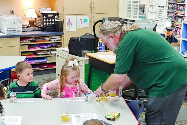 Snyder Primary School kindergarten teacher David Miller (right) helped Gracen Cheyne (left) and Marley Tinker with their coloring projects this morning. Today was the first day of classes for Snyder ISD students.