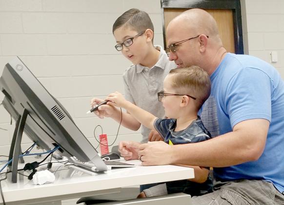 Snyder fourth grader Luke Lawson shows his brother Jase and father Jason how to use the ZSpace 3-D computers during Saturday’s Maker Faire.