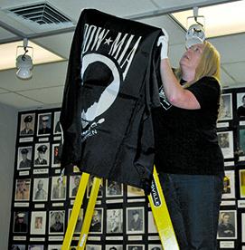 Museum Executive Director Nicole DeGuzman hangs a banner. The exhibit is being held in conjunction with Western Texas College’s Veteran’s Day ceremony Monday.