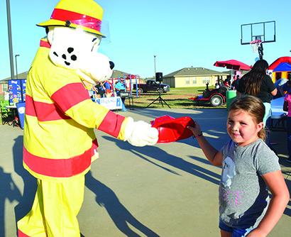 Kylie Perez, 6, received a plastic firefighter’s helmet from Sparky the fire dog during National Night Out at The Villages at Snyder Tuesday night.