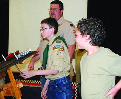 Joe Cheyne, 12, prepared to release the starting blocks for a race at the Pinewood Derby Saturday as Connor Reese, 8, and Lone Star District Executive Zackary Mullins look on. 