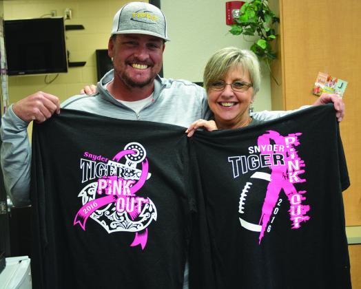 Snyder High School head football coach Cory Mandrell (left) and Snyder ISD athletic department secretary Rhonda Ward display the two shirt designs for this year’s Friday Night Fight football game on Oct. 21 against Wylie.