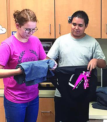 Snyder High School students Rebekka McDowell and Ruben Munoz fold Friday Night Fight T-shirts in the athletic office. The shirts may be picked up at The Embroidery Shop beginning at 5 p.m. today.
