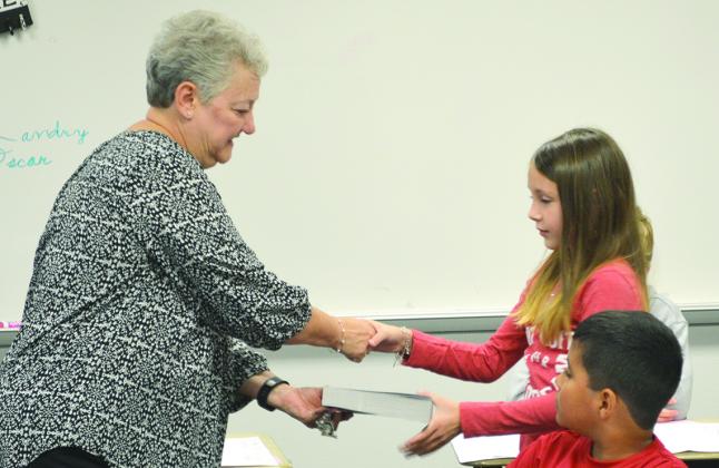 Snyder Rotary Club member Linda Jones hands a dictionary to Ira ISD third grader Mia Shultz as part of the Rotary Club’s literacy program.