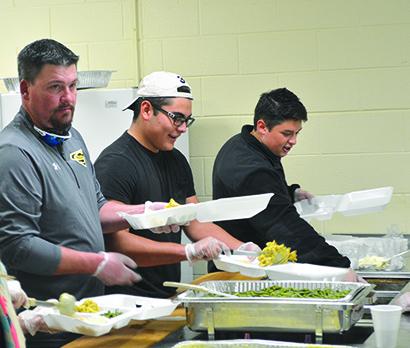 Pictured (l-r) Snyder High School Football Coach Cory Mandrell and Snyder High School students Alex Jaimes and Marcus Rocha helped fill boxes will food at the Rotary Club of Snyder’s annual Thanksgiving meal Thursday.