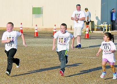 Snyder Deputy Fire Marshal Nathan Hines (background) watches (l-r) Gunner and Cason Hines and Imeri Madrid began the fun run at Saturday’s Running for the Heroes event in Towle Park. More than $4,000 will be donated to law enforcement officers injured in the line of duty, including Snyder police Cpl. Darrell Campbell.