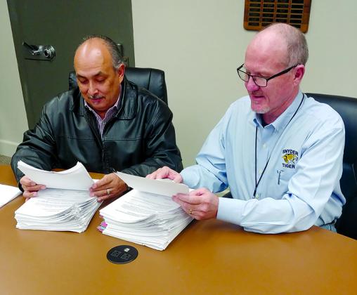 Snyder ISD School Board President Ralph Ramon (left) and Superintendent Dr. Eddie Bland look through some of the petitions signed by Snyder Junior High School parents and other members of the community in support of a plan to close the junior high school. The community petitions, in response to pending state sanctions against the district, also support a plan to realign the majority of grades in the school district.