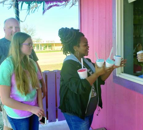 Chris Bird, left, and Isabel Bird, 13, wait their turn as Kiki Melhado collects snow cones for her family at Flamingo Pink’s snow cone stand Friday.  Flamingo Pink’s worker Janet Hernandez said the stand, located in the 3600 block of College Ave, opened March 1. “Business has been good,” she said. “We’ve been busy every day.”