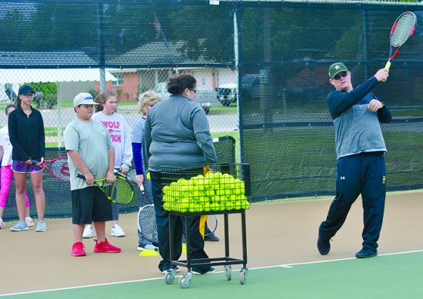 Snyder head tennis coach Coby Hamlin (right) gives pointers to students participating in the SHS Tennis Camp, which began today at the Snyder ISD tennis courts.