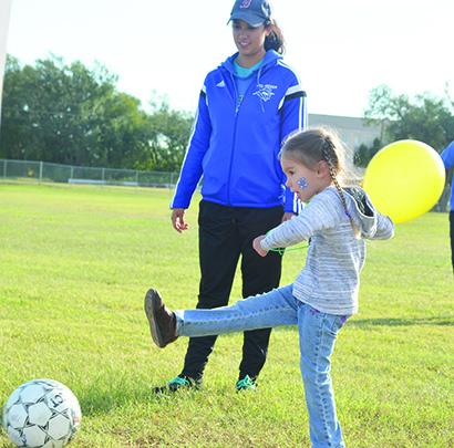 Beth Hughes, 4, kicked a soccer ball as hard as she could at SoctoberFest at The Coliseum Saturday. Western Texas College soccer player Myra Ibarra looked on.