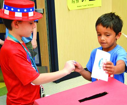 John Gregory (left), 8, helped Israel Martinez, 8, submit his ballot at the mock election at Snyder Primary School on Wednesday.