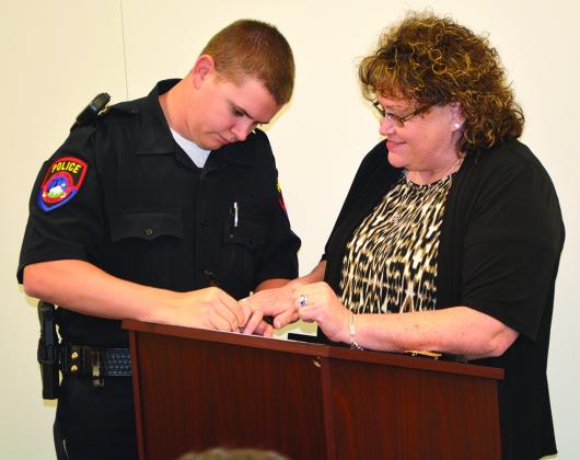 New Snyder police Officer Rustin Webb (left) signed his contract after being sworn in by his mother, Pct. 2 Justice of the Peace Ricki Webb.