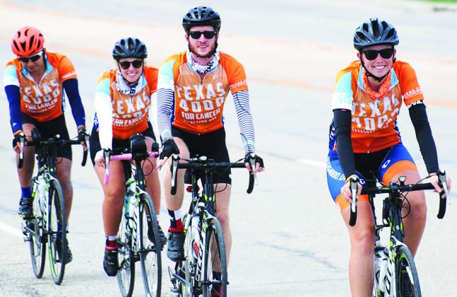 From left Kayla Leonard, Elizabeth Knoble, Kyle Campbell and Khoi Le were all smiles as they rode into Snyder on College Ave. Tuesday. The group of 24 University of Texas students are traveling to Alaska by bicycle to raise money and awareness for cancer prevention. 