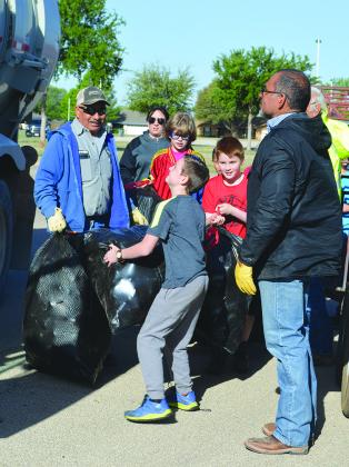 Fifth grader Mickey Hicks (center) through a bag of water bottles into a City of Snyder truck.