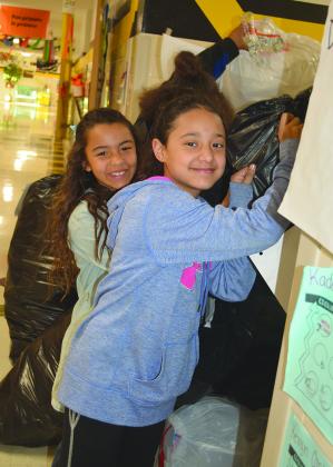 Fourth graders Kyera Short (left) and Grace Valadez piled bags of waterbottles.